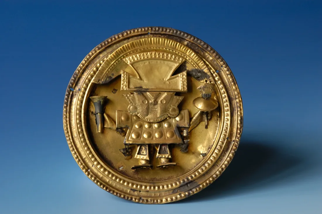 Ear peg disc, depicting figure in ceremonial robes, made of wrought and engraved gilt copper sheet